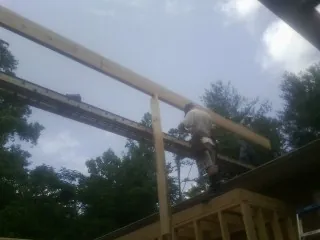 Carpenter setting a ridge beam over a new addition frame — Ice Dam Removal by Roofing Brothers in Tivoli