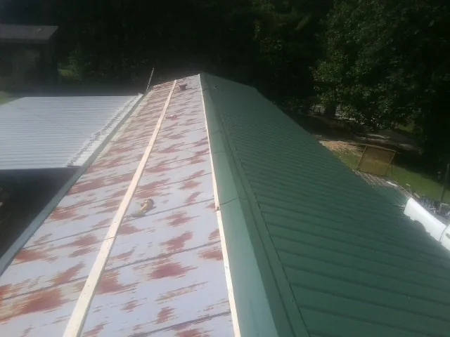 Old rusted panels beside newly installed green metal roofing — Wind Damage Roof Repair by Roofing Brothers in Tivoli