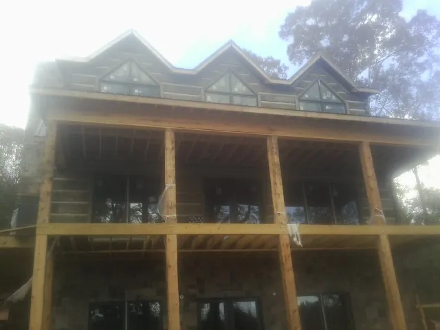 Dormers and porch framing on a large log home under construction — Roof Coating work by our crew in Tivoli