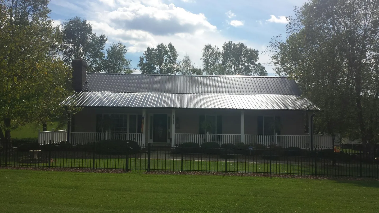 Gray metal roof on a brick ranch with a full width front porch — Gutter Guard Installation work by our crew in Tivoli