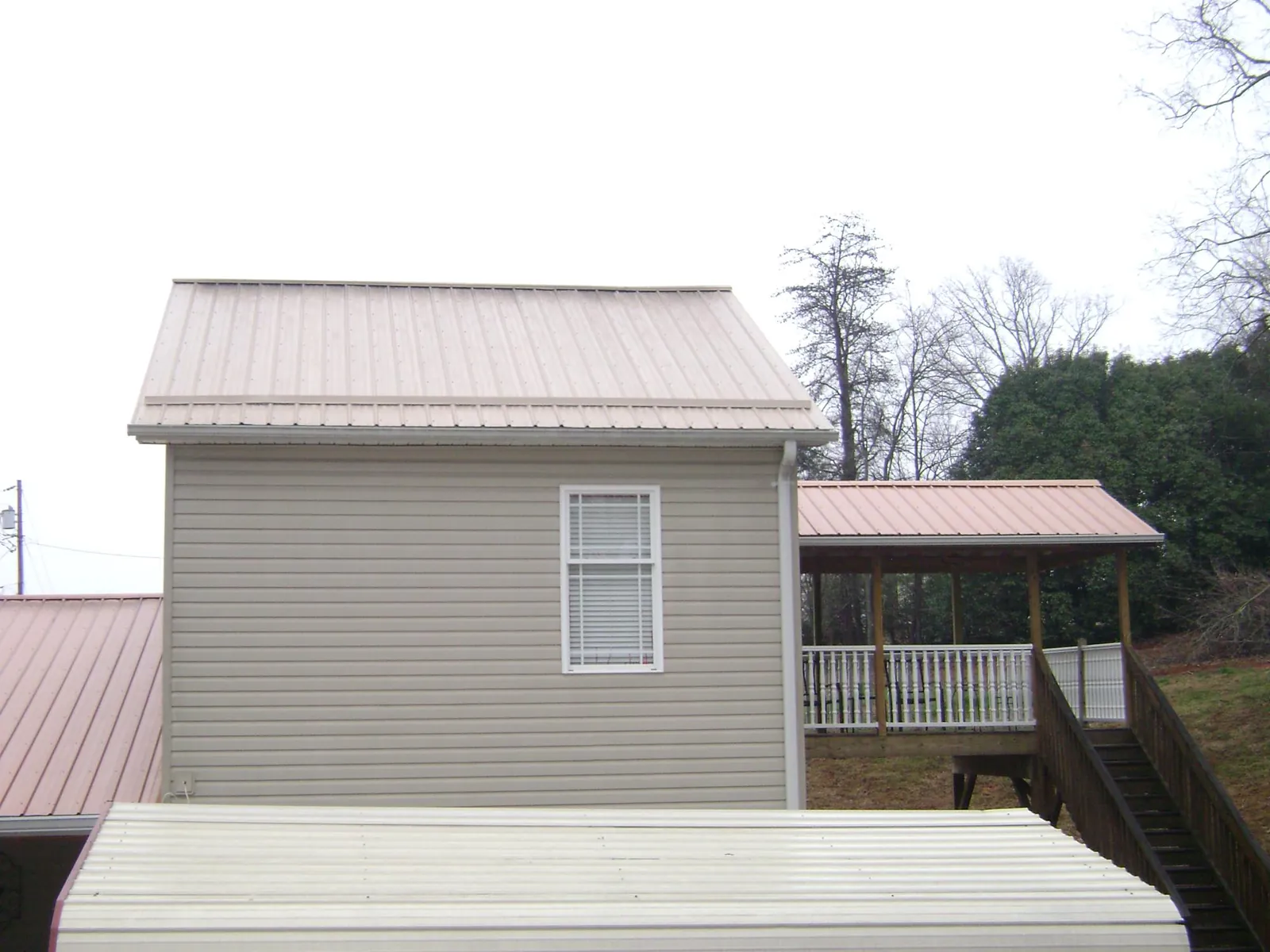 Tan metal roofs on a two story addition and attached porch, from a Roof Replacement job in Tivoli