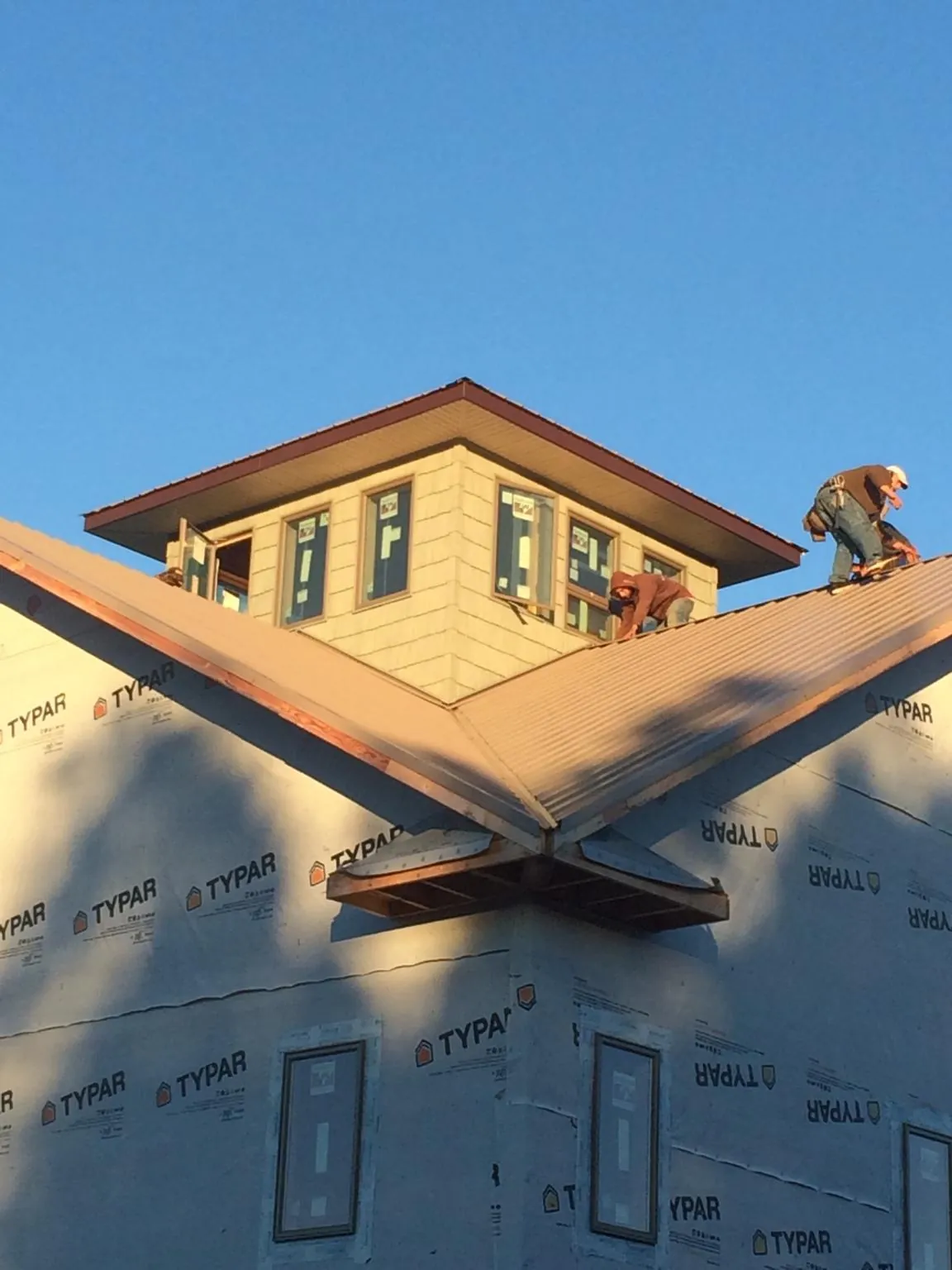 Roofers working around a rooftop cupola on a new metal roof at sunset — Roof Waterproofing in Tivoli by Roofing Brothers